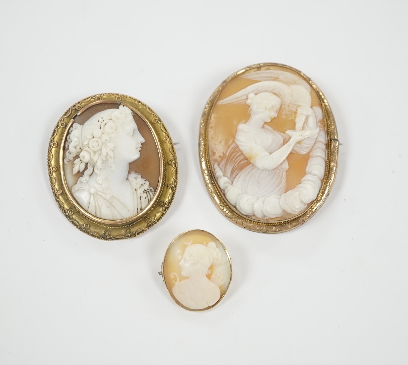 Two yellow metal mounted oval cameo shell brooches, the largest depicting Diana and the Eagle, 55mm and one other gilt metal mounted oval cameo shell brooch.